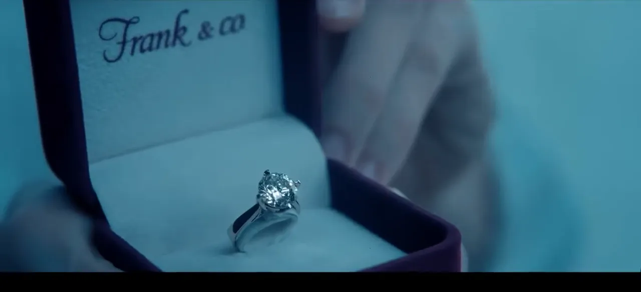 A diamond ring in an open box, catching soft window light